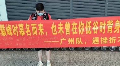 广州球迷机场迎接广州队，拉出“未曾在你低谷时背身离开”横幅