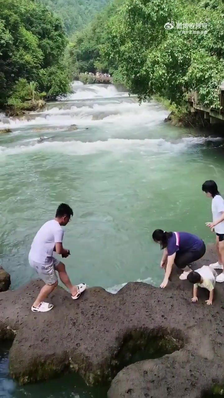 妈妈想把儿子拉到中间不慎碰到边上的女儿，女儿重心不稳掉进水里