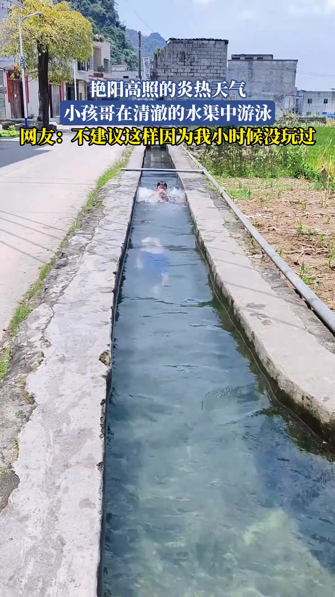 艳阳高照的炎热天气，小孩哥在清澈的水渠中游泳！
