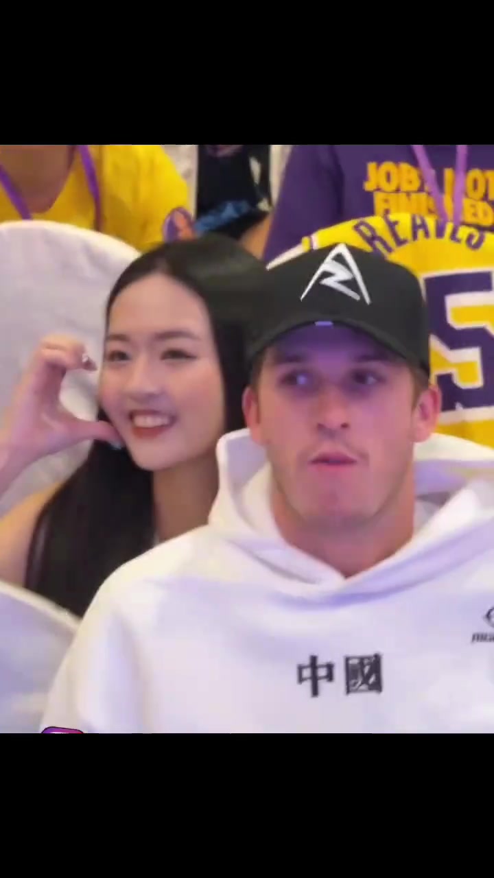 女球迷在里夫斯背后比心合影把小里都给整害羞了