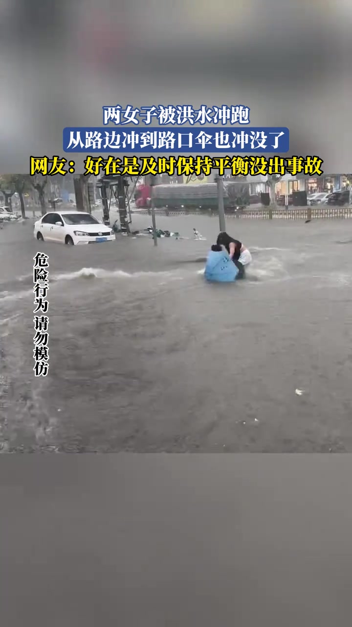 两女子被洪水冲跑，从路边冲到路口伞也冲没了