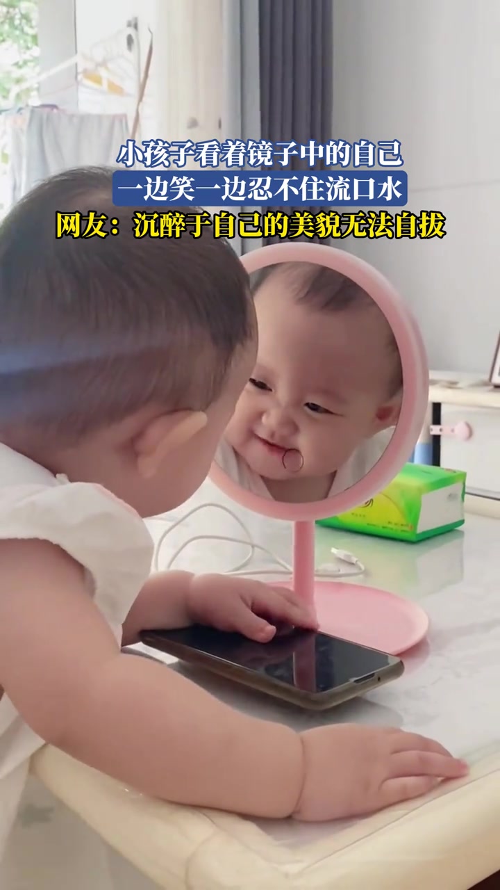 小孩子看著鏡子中的自己，一邊笑一邊忍不住流口水