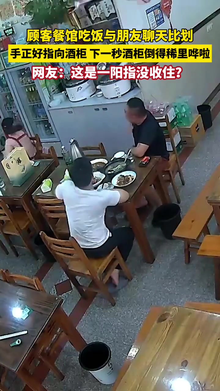 顾客餐馆吃饭与朋友聊天比划，手正好指向酒柜下一秒...