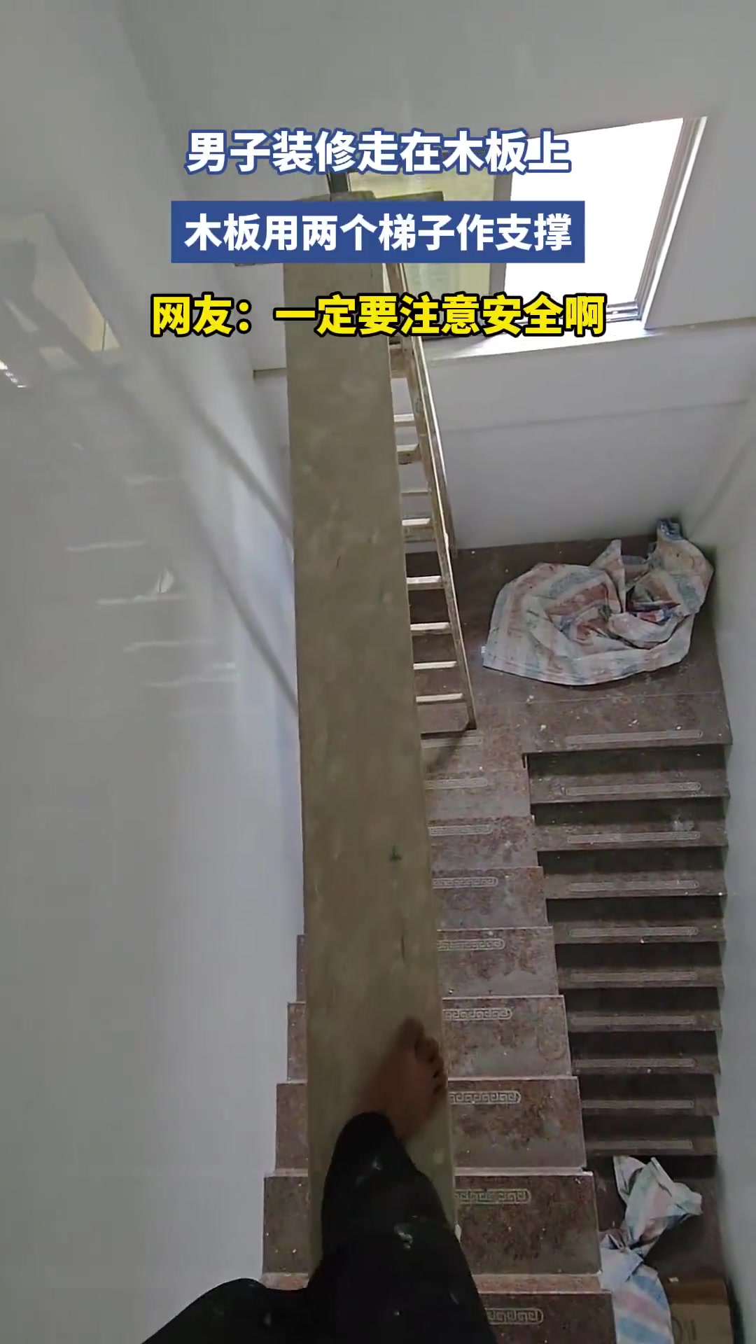 男子装修走在木板上，木板用两个梯子作支撑