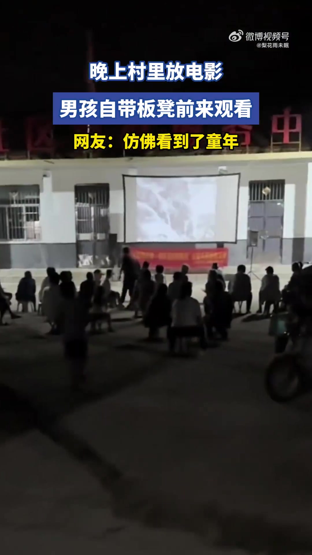 晚上村里放电影，男孩自带板凳前来观看
